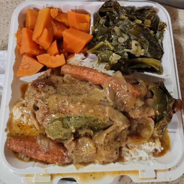 A Timeless Treat soul food meal with smothered pork chops, rice, collard greens, and candied yams.